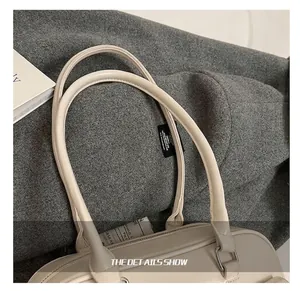 Detail showing thickened shoulder strap and metal hardware on cream leather handbag