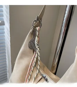 Close-up of beige faux leather tote bag with stylish tennis racket pendant and braided rope