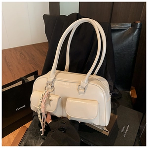 Detailed view of cream leather handbag with double pockets and star pendant accessory