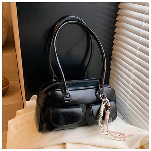 Detailed close-up of glossy black shoulder bag with double pockets and star charm
