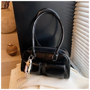 Close-up of black retro handbag featuring double front pockets and star tassel charm