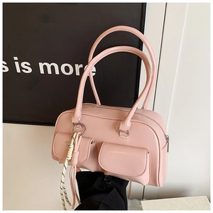 Detailed macro view of pink PU leather handbag showing dual front pockets and woven strap