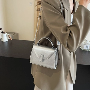 Sac à main argenté minimaliste avec boucle en métal porté par un mannequin