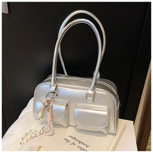 Close-up of metallic silver handbag with dual front pockets and woven knot charm detail