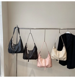 Detail of minimalist hobo bags with tassel accents in black, brown, pink, and beige colors