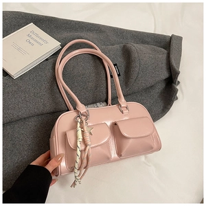 Detail of pink PU leather handbag showing side woven star charm and front flap pockets