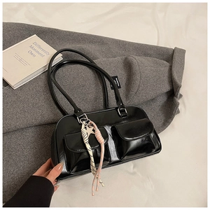 Detail of glossy black shoulder bag with cargo pockets and star charm accent