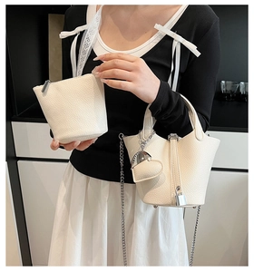 Detail of lychee pattern leather bucket bag with silver padlock and metal chain strap