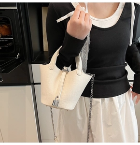 Detail of white lychee leather bucket bag with silver lock and metal chain strap