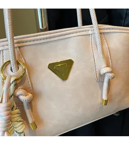 Gros plan du sac cabas rose avec logo LURADCA doré et pendentif décoratif tressé
