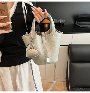 Detail showing grey pebbled leather bucket bag with metal lock and heart charm