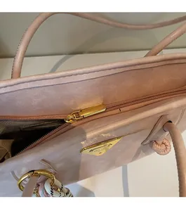 Détail d'un sac à main rose en similicuir avec fermeture éclair dorée et logo triangle
