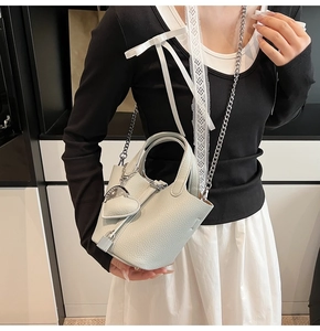 Close-up of light green pebble leather bucket bag with silver chain and heart charm