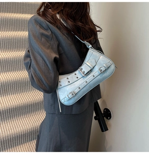 Sac sous le bras en similicuir bleu clair avec œillets métalliques porté par un mannequin