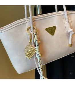 Vue détaillée du sac à main rose avec un pendentif boulier doré et plaque de marque