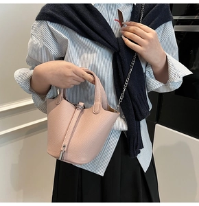 Pink lychee leather bucket bag with silver chain worn by a model in a casual outfit