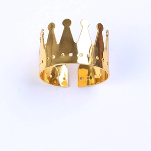 Detailed close-up of golden crown napkin ring with a polished metallic finish on white back