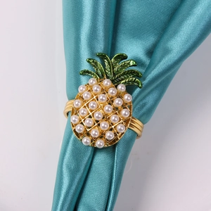 Rond de serviette ananas doré avec perles blanches et feuilles vertes sur soie bleue