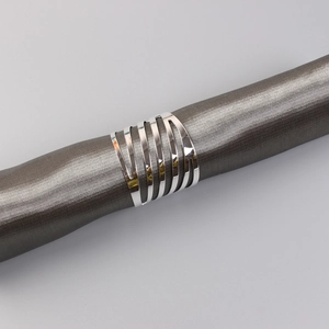 Detail of silver hollowed multi-layered metal napkin ring with mirror finish on fabric