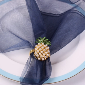 Vue détaillée du rond de serviette ananas avec perles blanches et émail vert décoratif