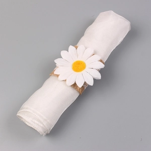 Detailed view of burlap daisy napkin ring with white lace edges on a white rolled cloth