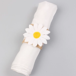 Daisy napkin ring with natural jute burlap strap on a white cloth napkin, farmhouse style