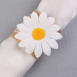 Detailed close-up of daisy napkin ring with burlap base and white lace edge on fabric