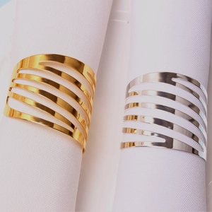 Close-up of gold and silver hollowed stripe napkin rings on white fabric napkins