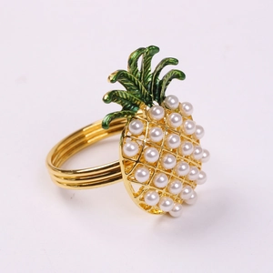 Gros plan d'un rond de serviette ananas doré avec perles blanches et émail vert décoratif