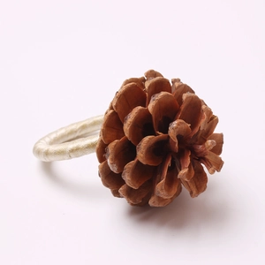Christmas pine cone napkin ring with golden thread on a clean white background
