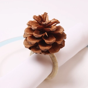Close-up of a natural pine cone napkin ring on a white napkin for rustic Christmas table decor