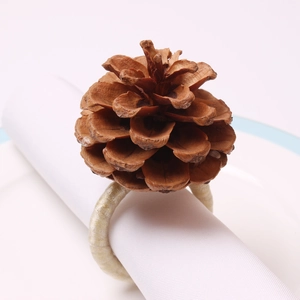 Close-up of a natural pine cone napkin ring on white cloth over a ceramic plate