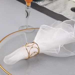 Macro shot of gold wire-wrapped napkin ring with diamond accents on white mesh fabric