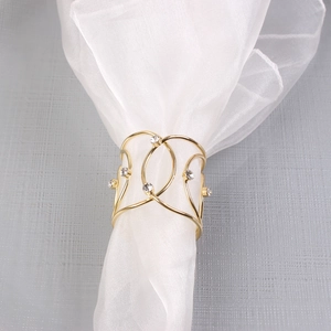 Macro shot of gold napkin ring with woven X design and sparkling diamond accents