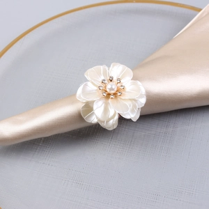 Elegant pearl and acrylic flower napkin ring on champagne silk for luxury wedding table decor