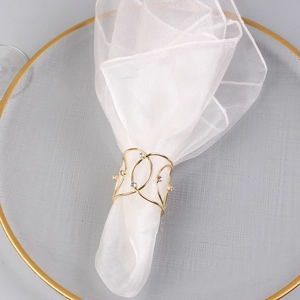 Elegant gold metal napkin ring with diamond accents on a white fabric background