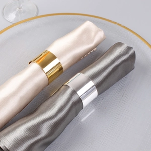 Mirror polished gold and silver metal napkin rings on elegant glass plates set