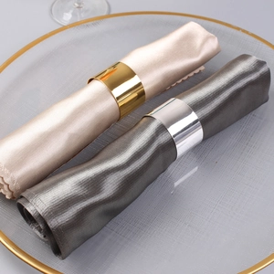 Close-up of polished gold and silver metal napkin rings on elegant satin napkins