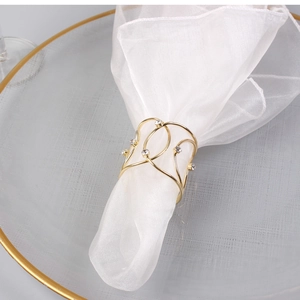 Close-up of golden woven napkin ring with sparkling rhinestones on a white fabric napkin