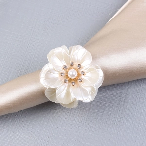 Detailed macro view of white acrylic floral napkin ring with pearl and rhinestone center