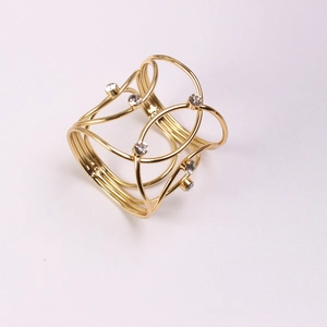Detail of gold napkin ring with woven hollow metal wire design and inlaid rhinestones