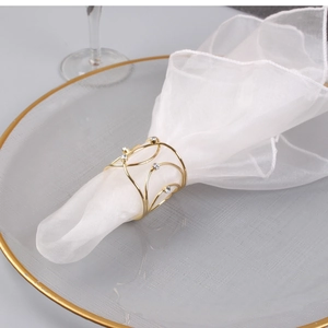 Detail of gold X-shaped napkin ring with crystal accents on a white fabric napkin