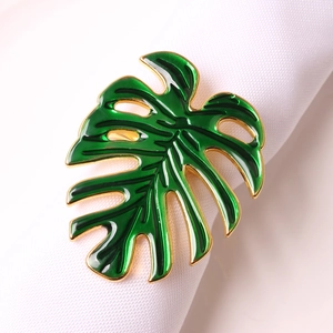 Vue macro d'un rond de serviette feuille de monstera tropicale en émail vert et or