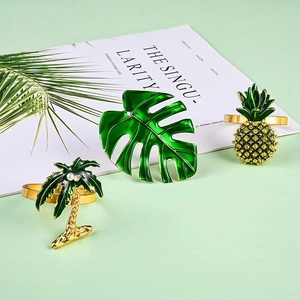 Détail de ronds de serviette tropicaux dorés avec feuille de monstera, ananas et palmier