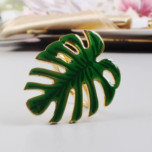 Gros plan du rond de serviette feuille de monstera vert avec base en métal doré et émail