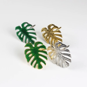 Détail de ronds de serviette en forme de feuille de monstera en finitions or, argent et émail