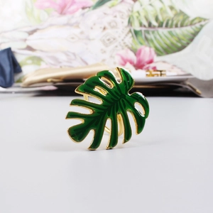 Vue macro du rond de serviette feuille de monstera doré avec finition émail vert