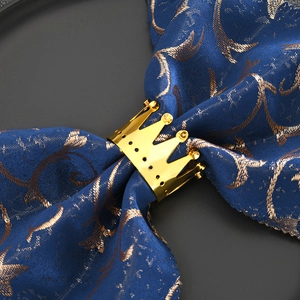 Elegant gold crown napkin ring with mirror finish on a navy blue napkin for wedding table