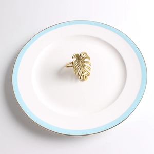Gros plan du rond de serviette feuille de monstera doré montrant la texture sur une assiette