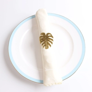Vue détaillée d'un rond de serviette doré en forme de feuille de monstera sur une serviette